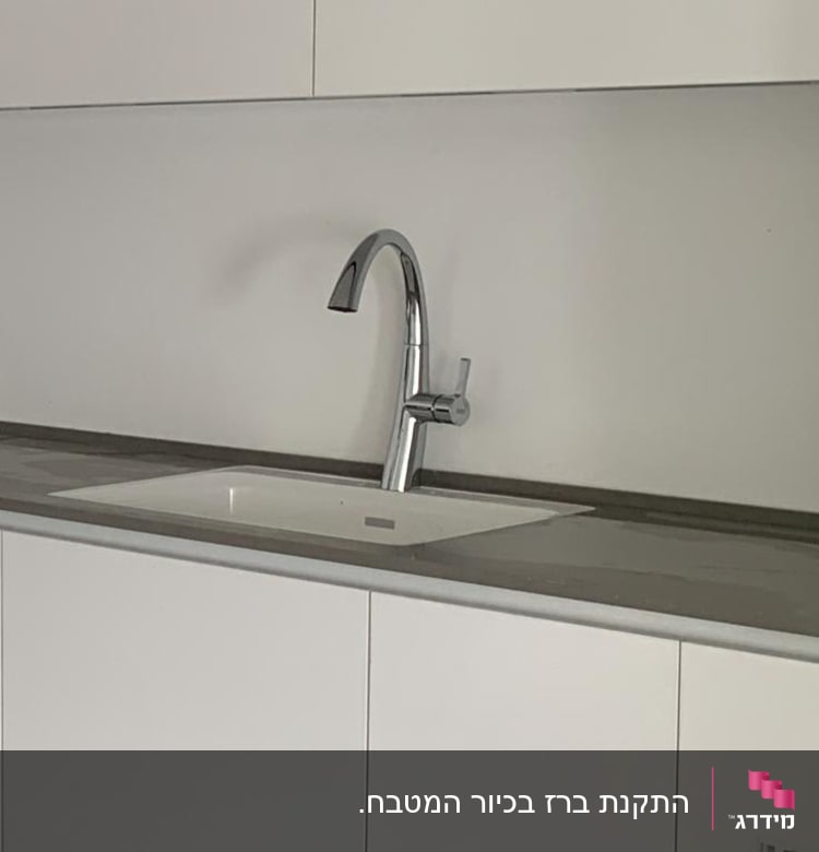 ברז מטבח כסוף מותקן על כיור לבן